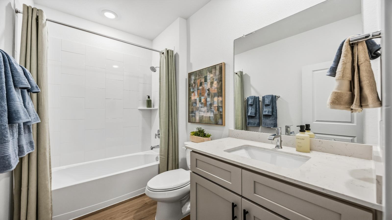 A well-designed bathroom equipped with quartz countertops, a standing tub, and a single vanity.