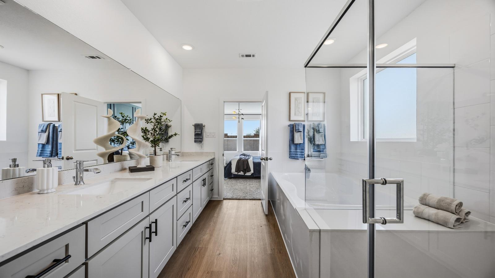 Luxurious primary bathroom with dual vanities, a soaking tub, glass-enclosed shower and walk-in closet.