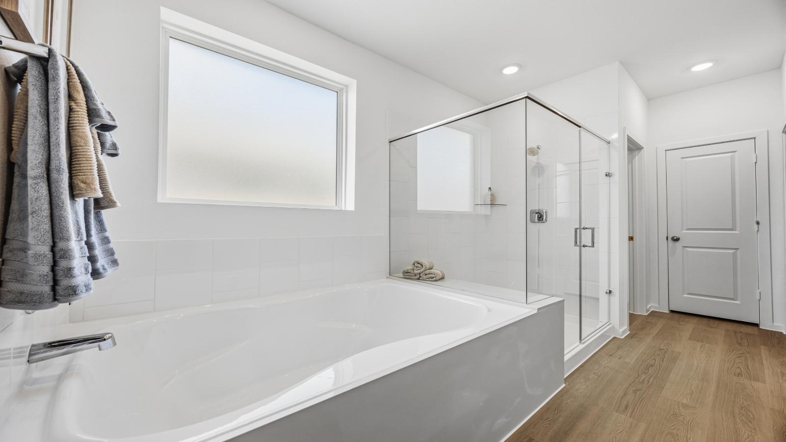 Primary bathroom with a glass-enclosed standing shower and separate soaking tub.