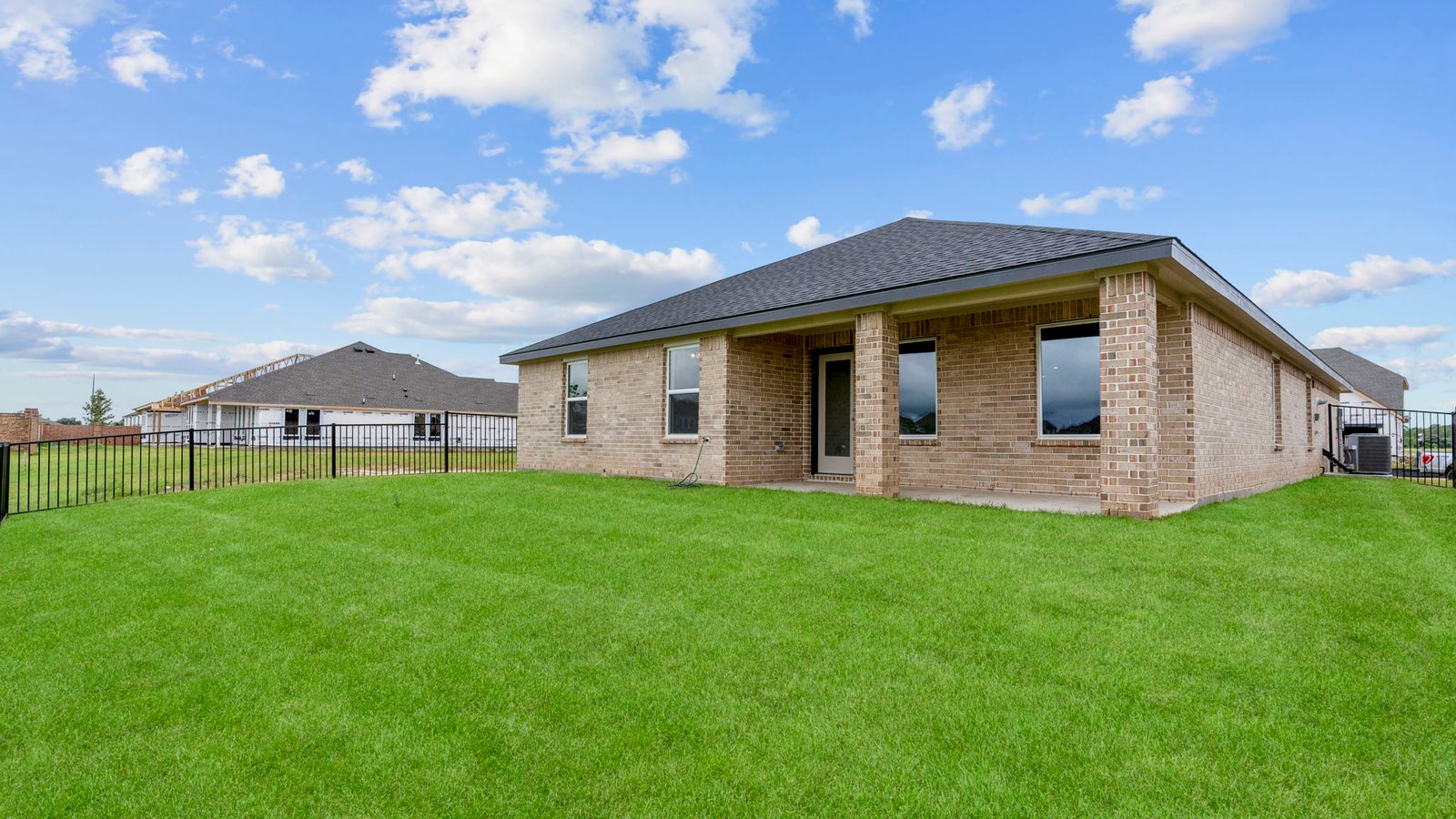 Outdoor covered patio with seating area overlooking a well-maintained lawn, perfect for relaxation.