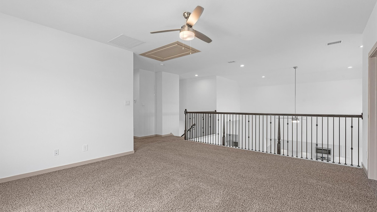 A spacious upstairs living area with plenty of natural light from windows overlooking side of the home