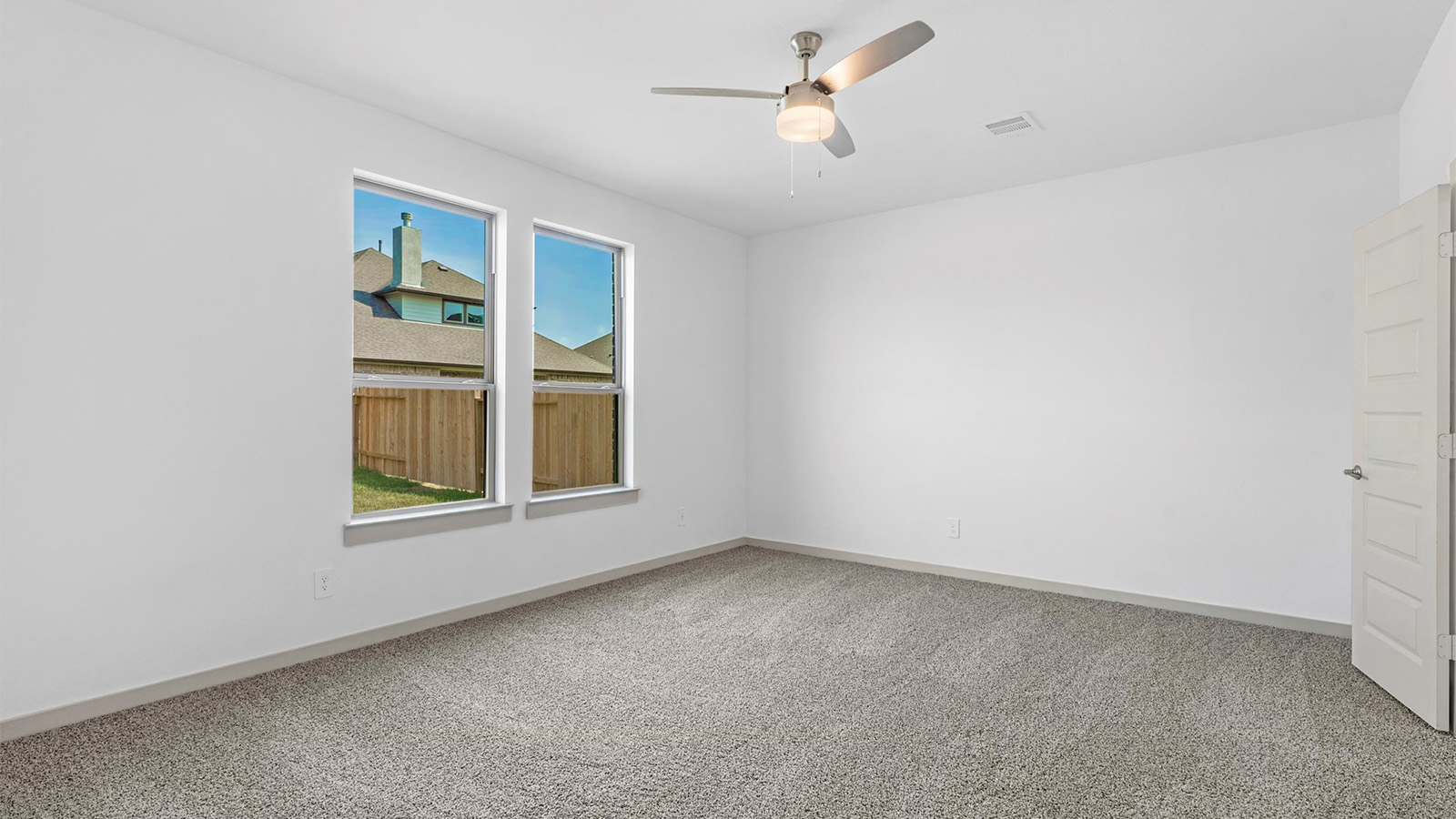 Primary bedroom with ceiling fan, plush carpeting, and a large walk-in closet.