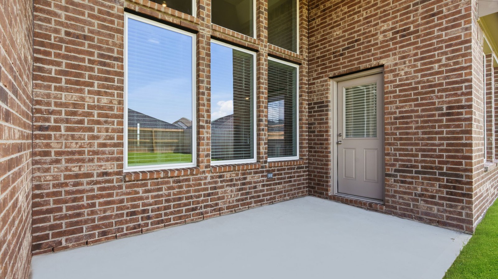 Outdoor covered patio with seating area overlooking a well-maintained lawn, perfect for relaxation.