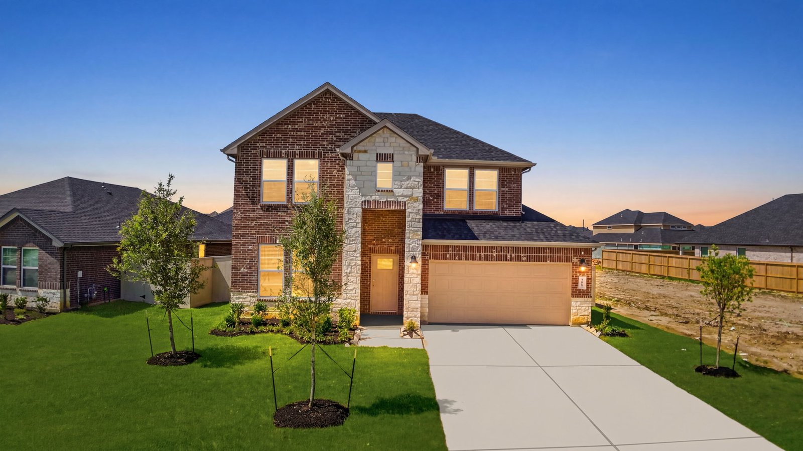 A two-story home a night with brick and stone exterior with a two-car garage and a well maintained front lawn in Texas City