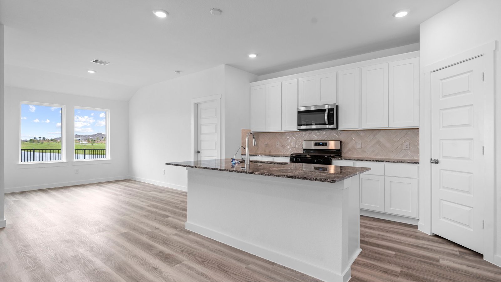Bright and spacious kitchen with granite countertops, stainless steel appliances, and an island with bar seating.