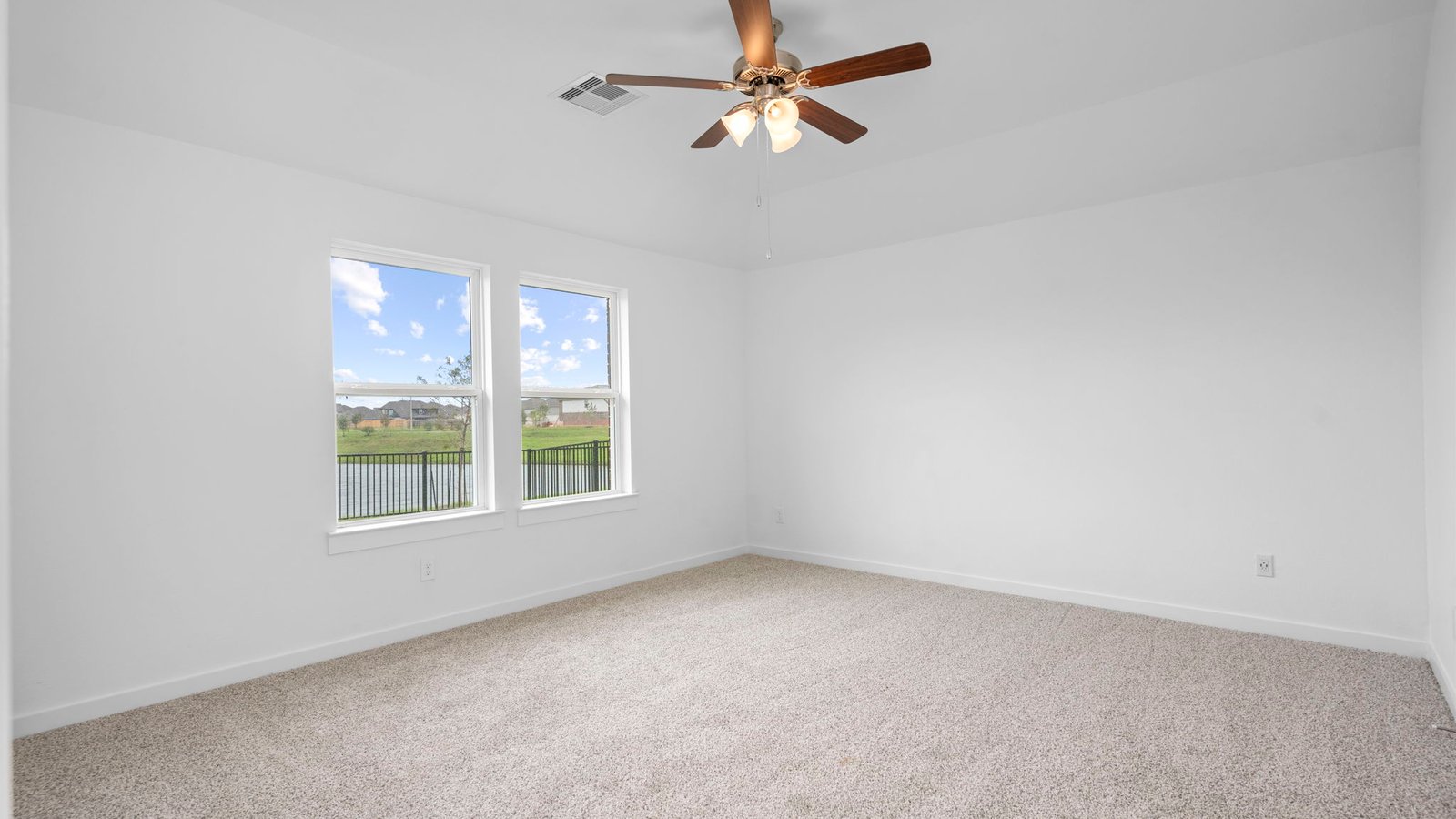 Primary bedroom with ceiling fan, plush carpeting, and a large walk-in closet.