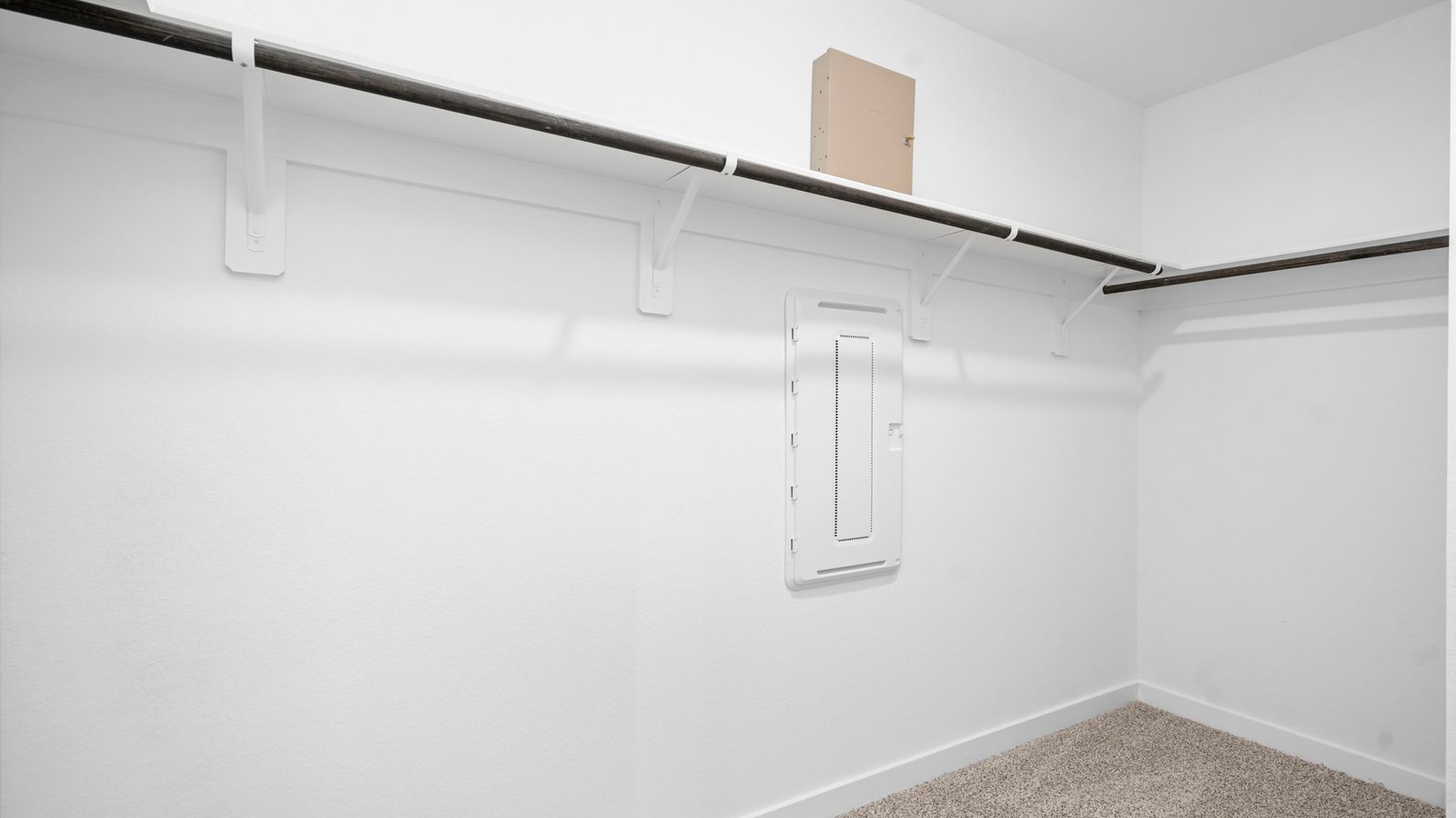 A spacious walk-in closet off the primary bathroom with multiple hanging rods, and shelves for maximum storage capabilities.