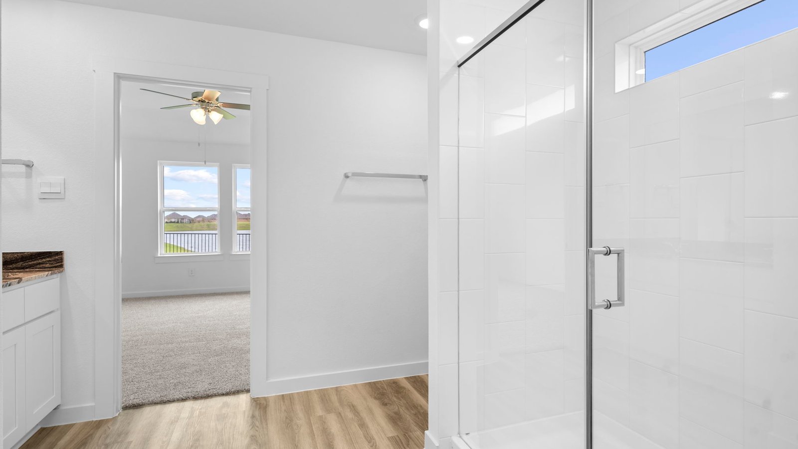 Modern primary bathroom with double vanities, granite countertops, and a glass-enclosed shower with a walk-in closet.