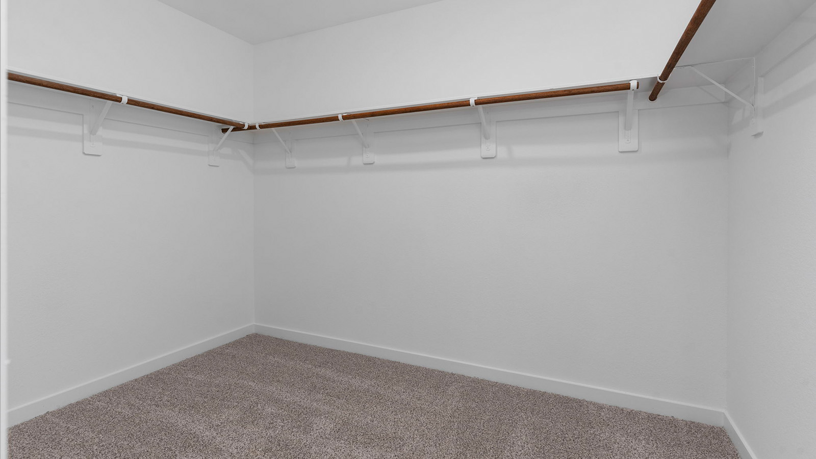A spacious walk-in closet off the primary bathroom with multiple hanging rods, and shelves for maximum storage capabilities.