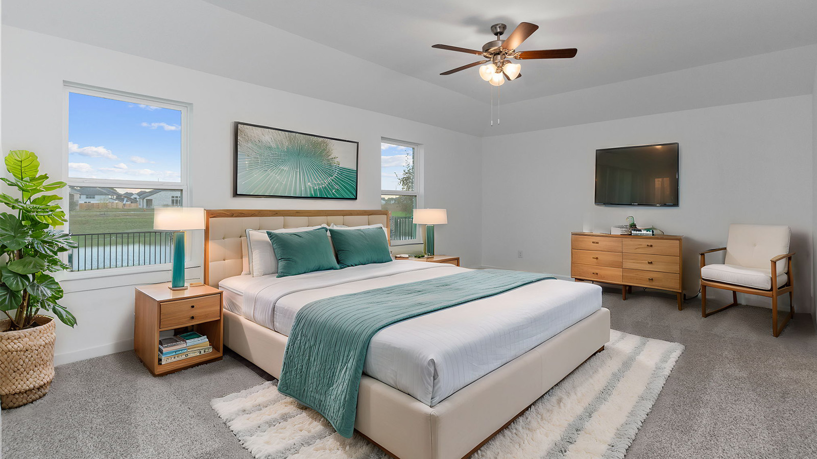 Primary bedroom with ceiling fan, plush carpeting, and a large walk-in closet.