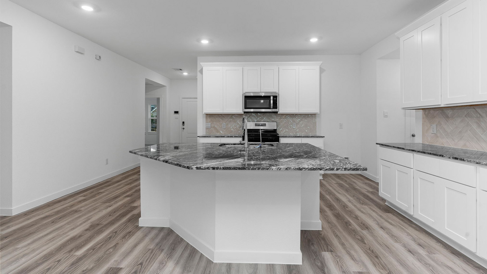Bright and spacious kitchen with granite countertops, stainless steel appliances, and an island with bar seating.
