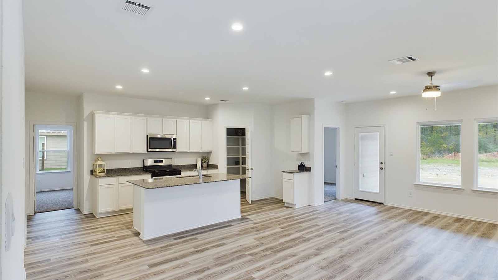 Open concept kitchen, dining, and living room with two large windows