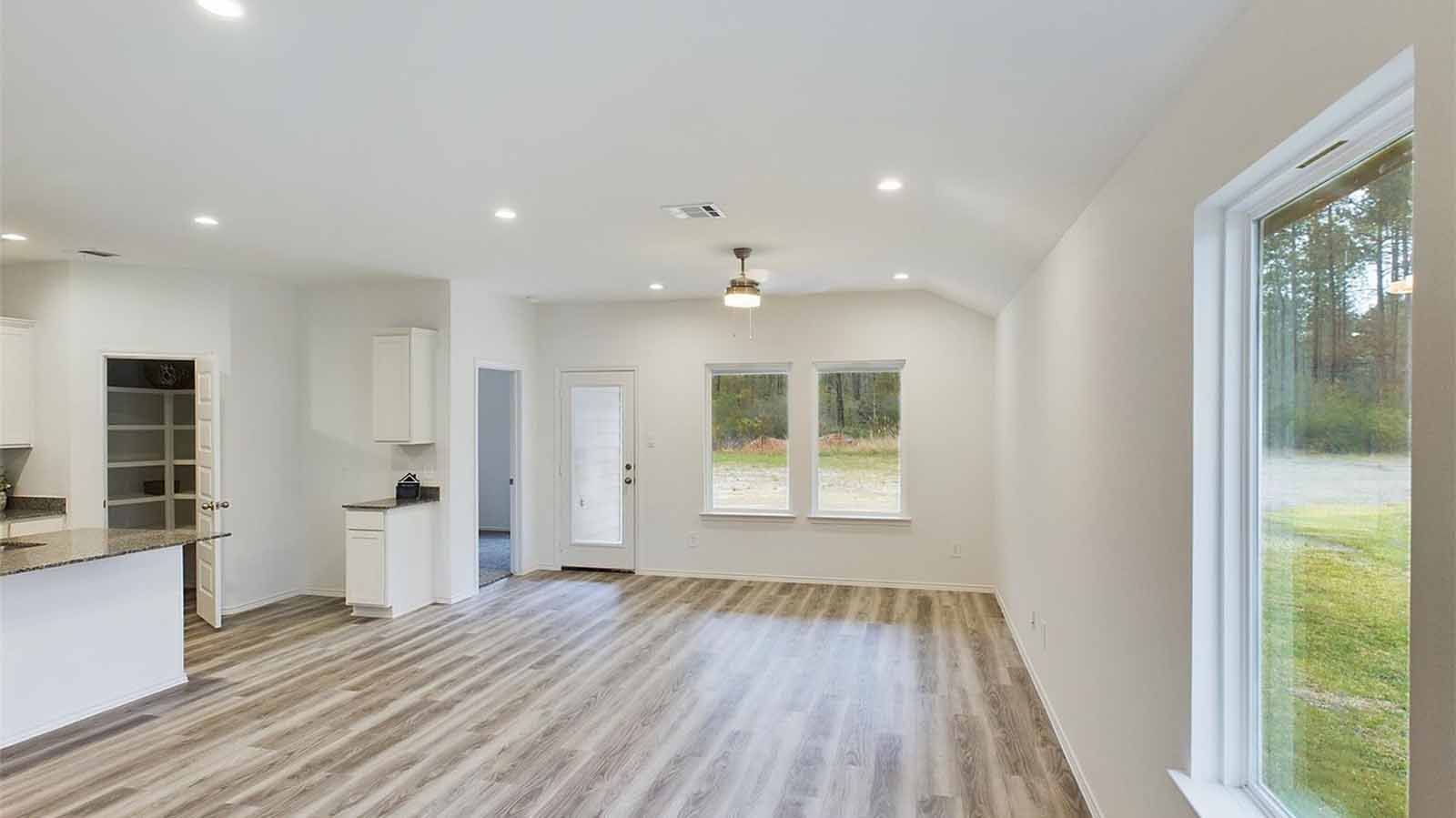 Open concept kitchen, dining, and living room with three large windows