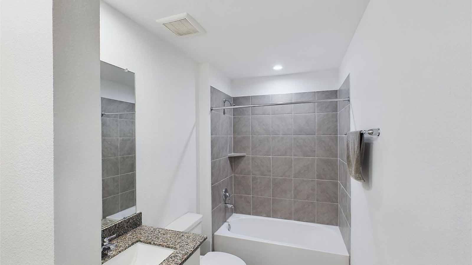 Secondary bathroom vanity with one sink and a large mirror and a bathtub/shower combo