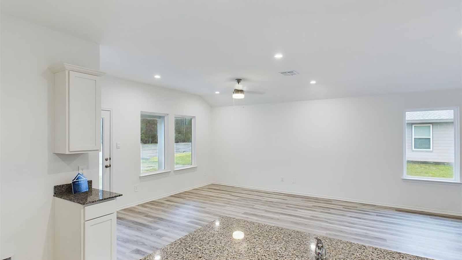 Open concept kitchen, dining, and living room with three large windows