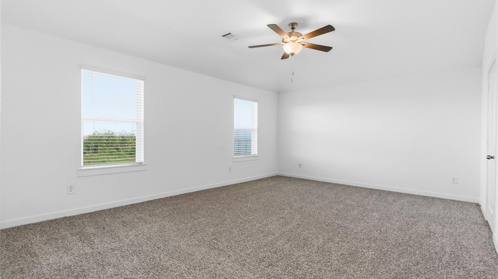 A spacious primary bedroom emphasizing open space and natural lighting with large windows.
