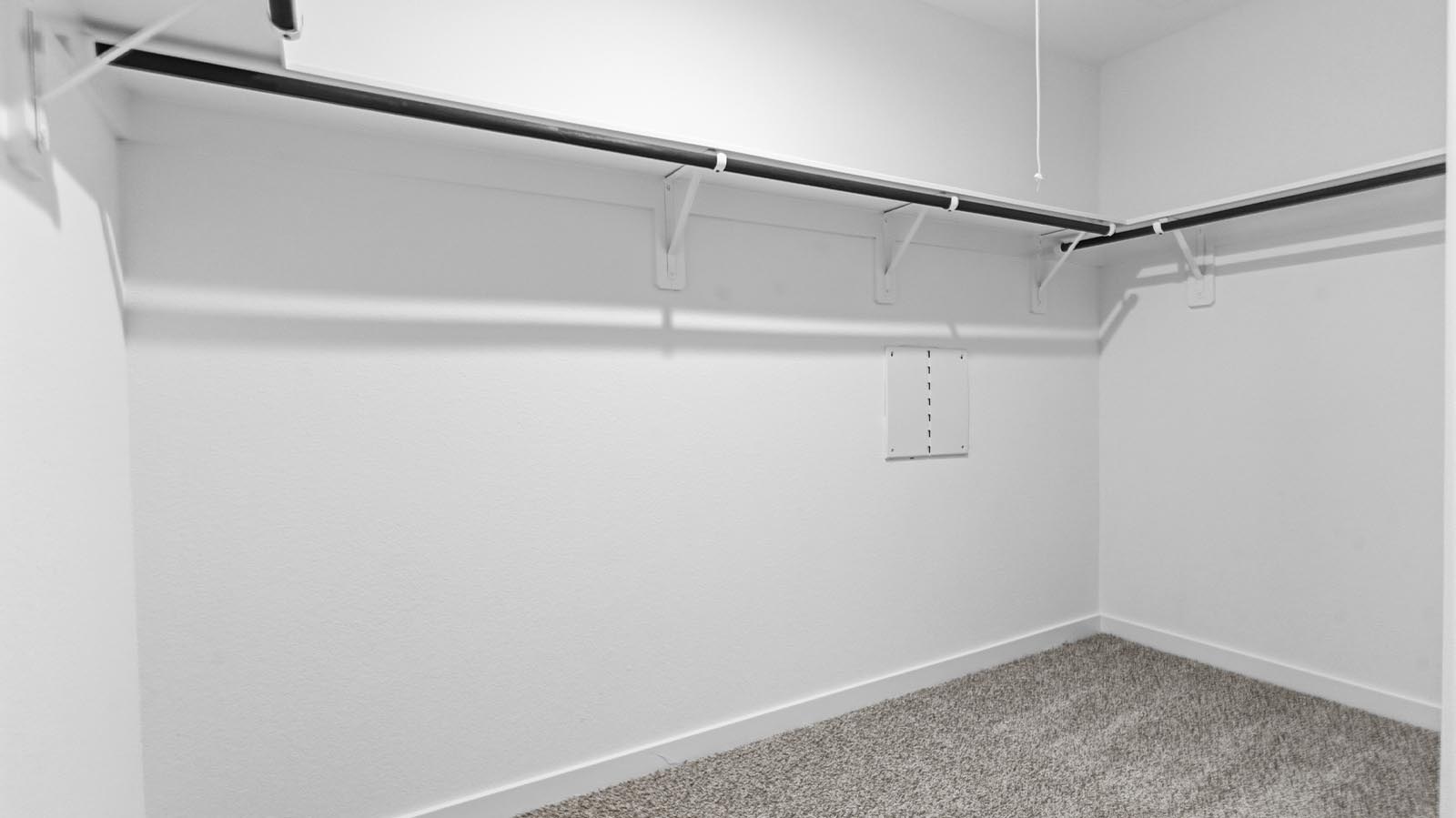 A spacious walk-in closet off the primary bathroom with multiple hanging rods, and shelves for maximum storage capabilities.