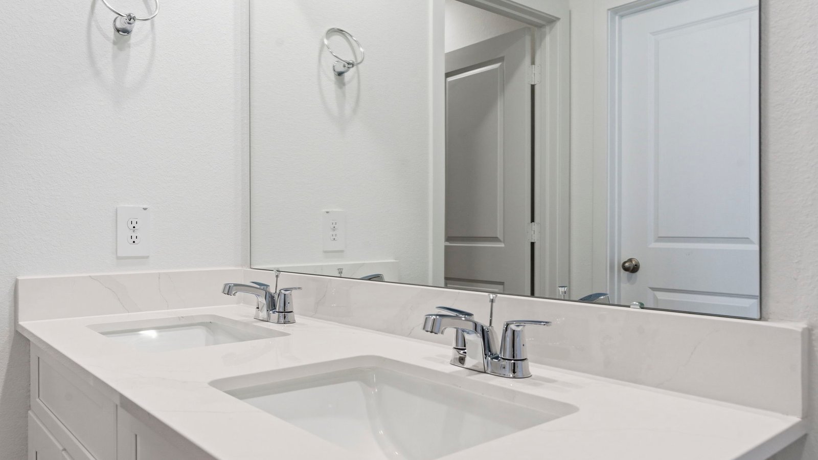 Modern primary bathroom with double vanities, granite countertops, and a glass-enclosed shower with a walk-in closet.