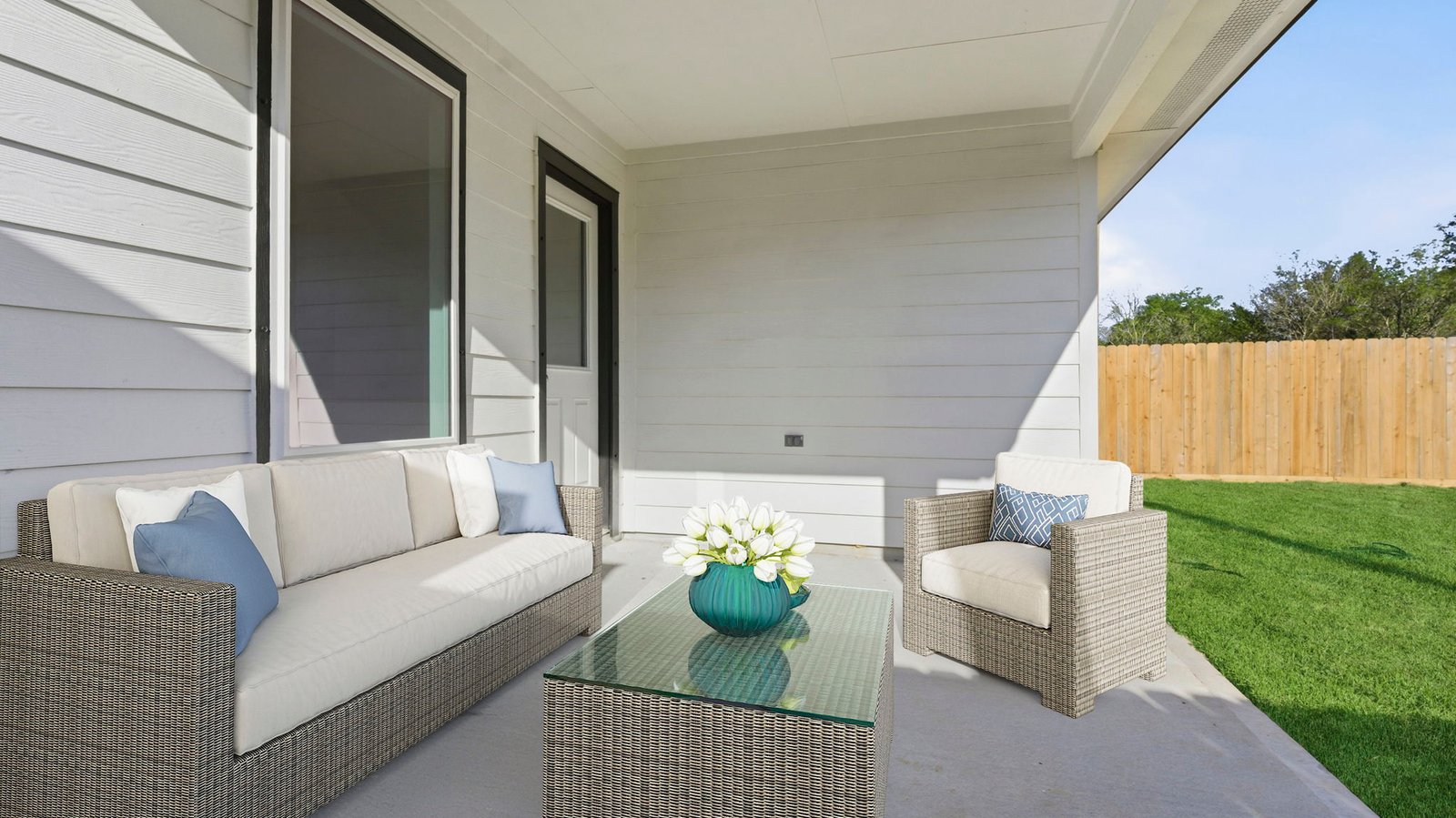 Outdoor covered patio with seating area overlooking a well-maintained lawn, perfect for relaxation.