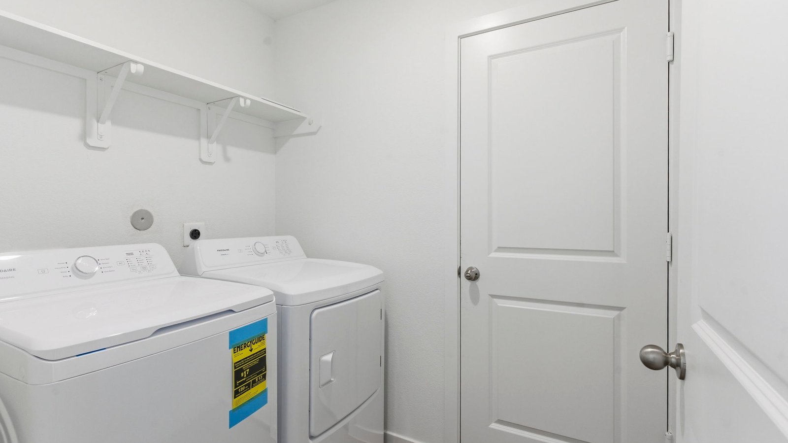 A laundry room featuring a washer and dryer, neatly arranged with ample space for laundry tasks and storage.