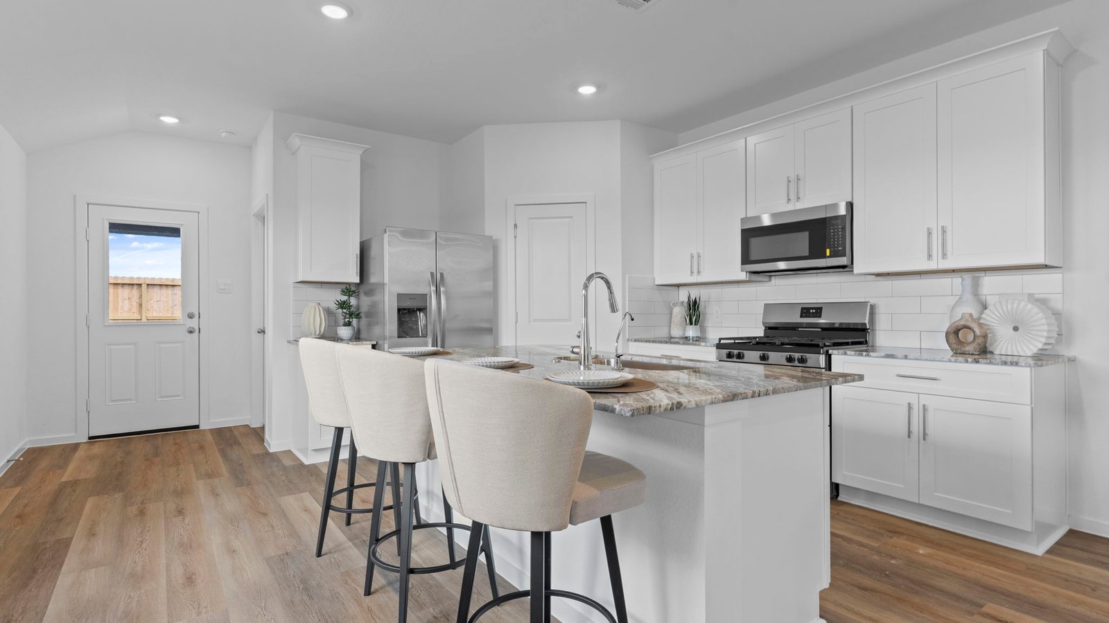 Bright and spacious kitchen with quartz countertops, stainless steel appliances, and an island with bar seating.