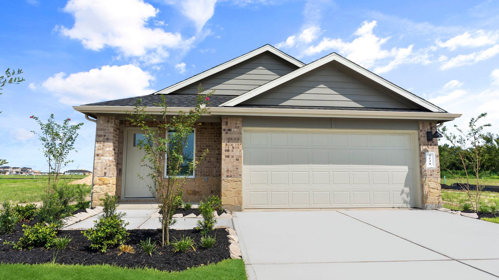 Side view of the newly built one story home with traditional architecture, a two car garage and a landscaped front yard