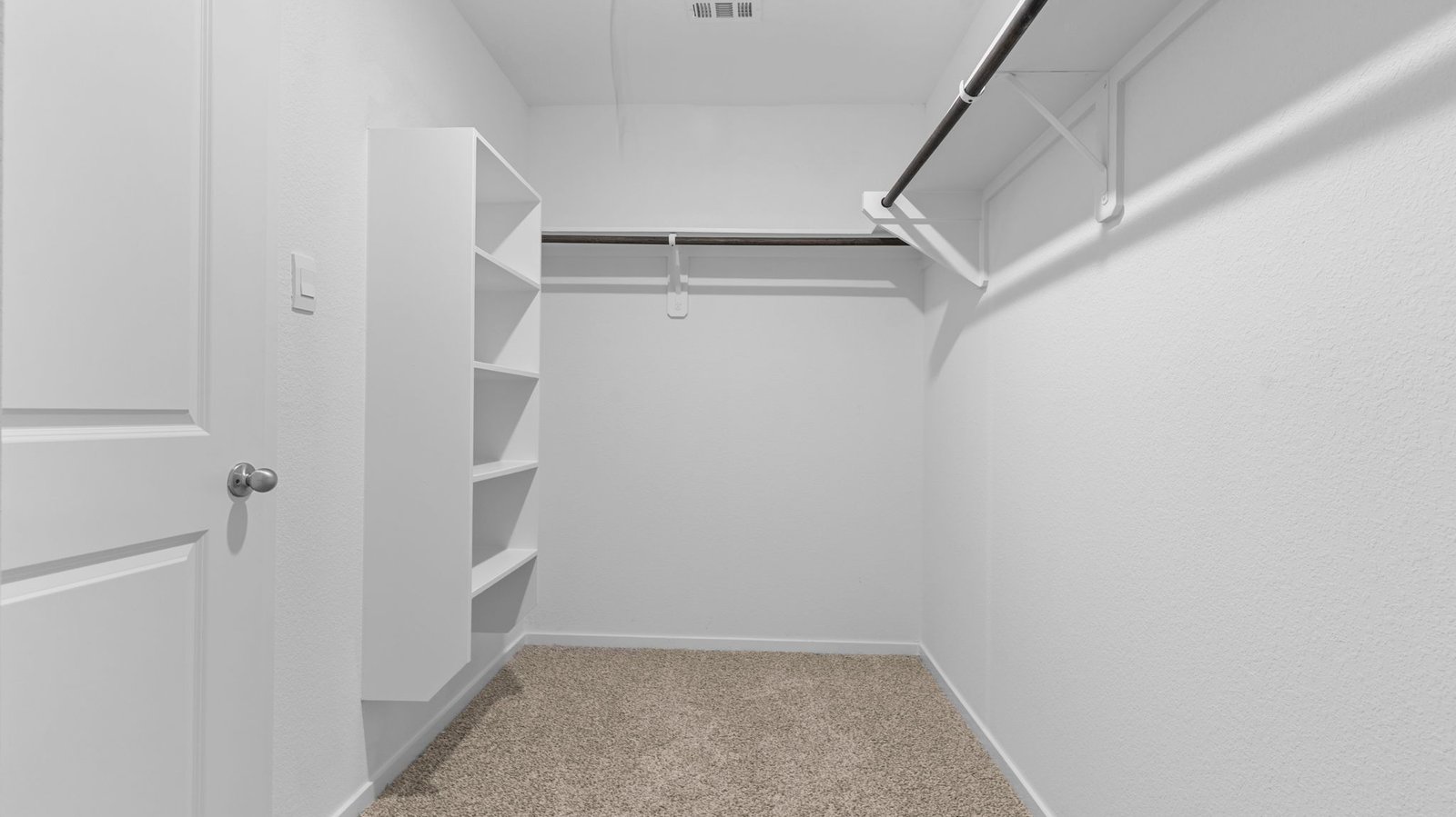 A spacious walk-in closet off the primary bathroom with multiple hanging rods, and shelves for maximum storage capabilities.