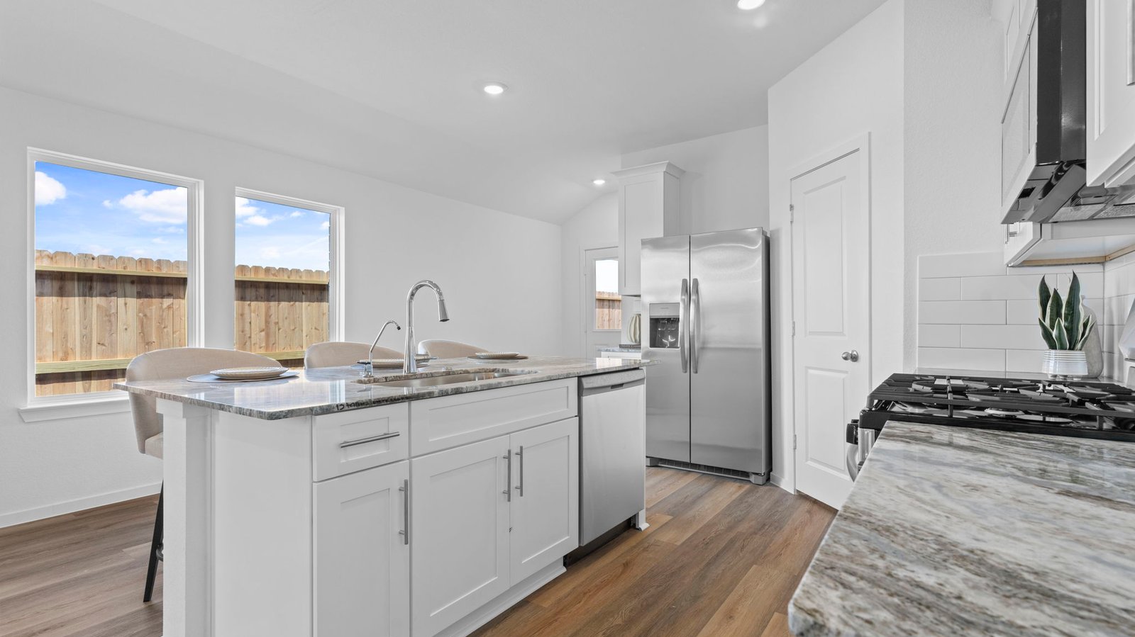 Kitchen adorned with white cabinets seamlessly integrated into an open dining area layout.