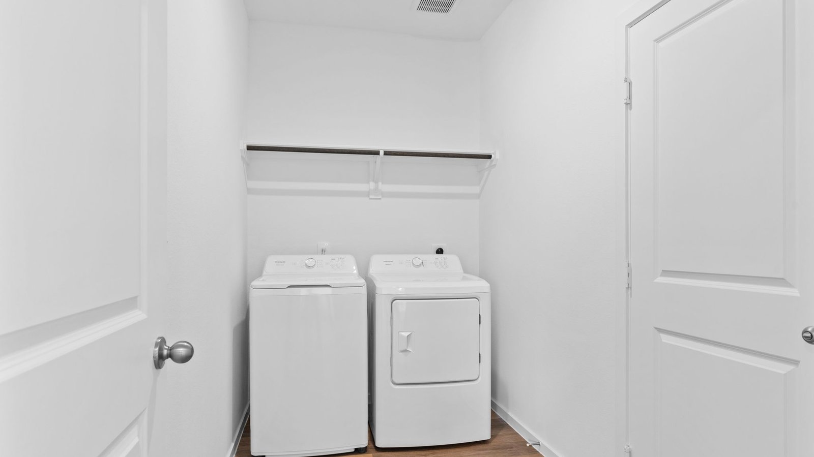 A laundry room featuring washer and dryer connections, neatly arranged with ample space for laundry tasks and storage.