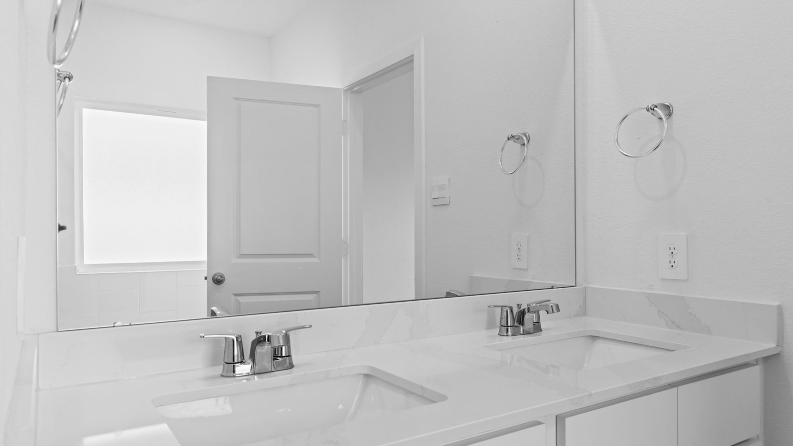 Modern primary bathroom with double vanities, quartz countertops, and a glass-enclosed shower with a walk-in closet.