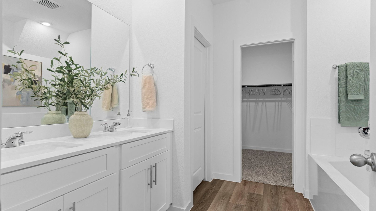 Modern primary bathroom with double vanities, granite countertops, and a glass-enclosed shower with a walk-in closet