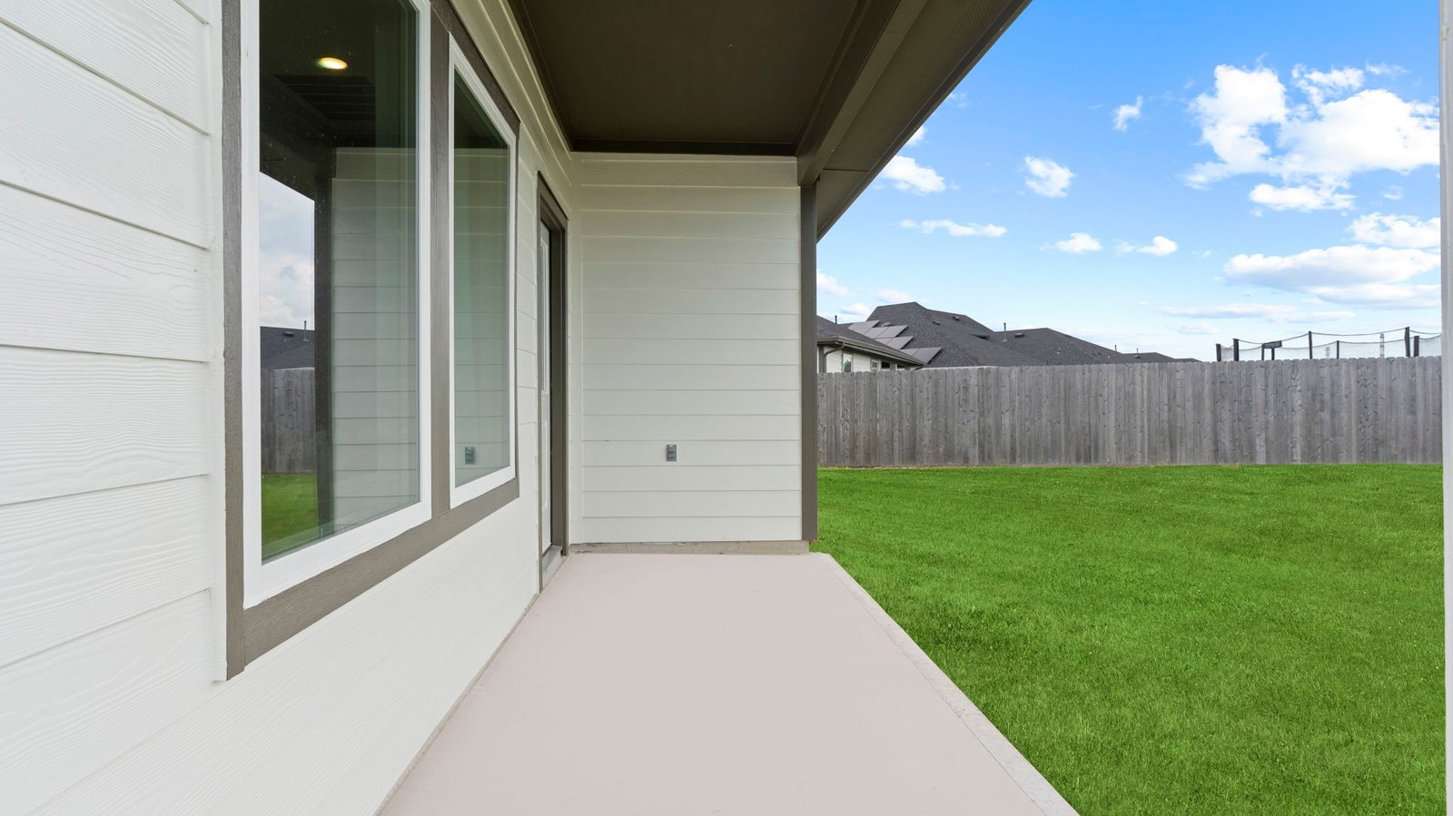 Outdoor covered patio with seating area overlooking a well-maintained lawn, perfect for relaxation.