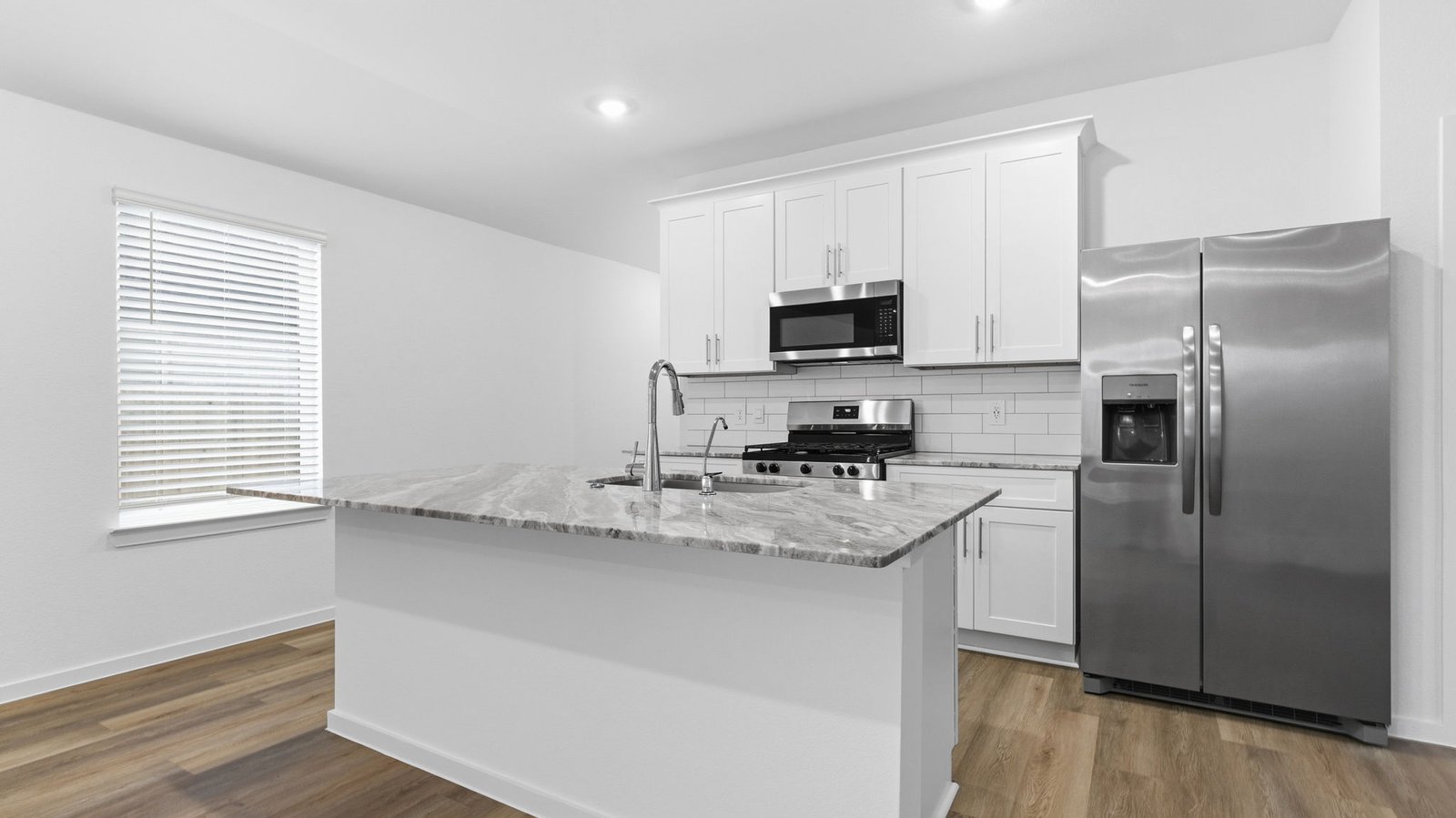 Kitchen adorned with white cabinets seamlessly integrated into an open dining area layout.