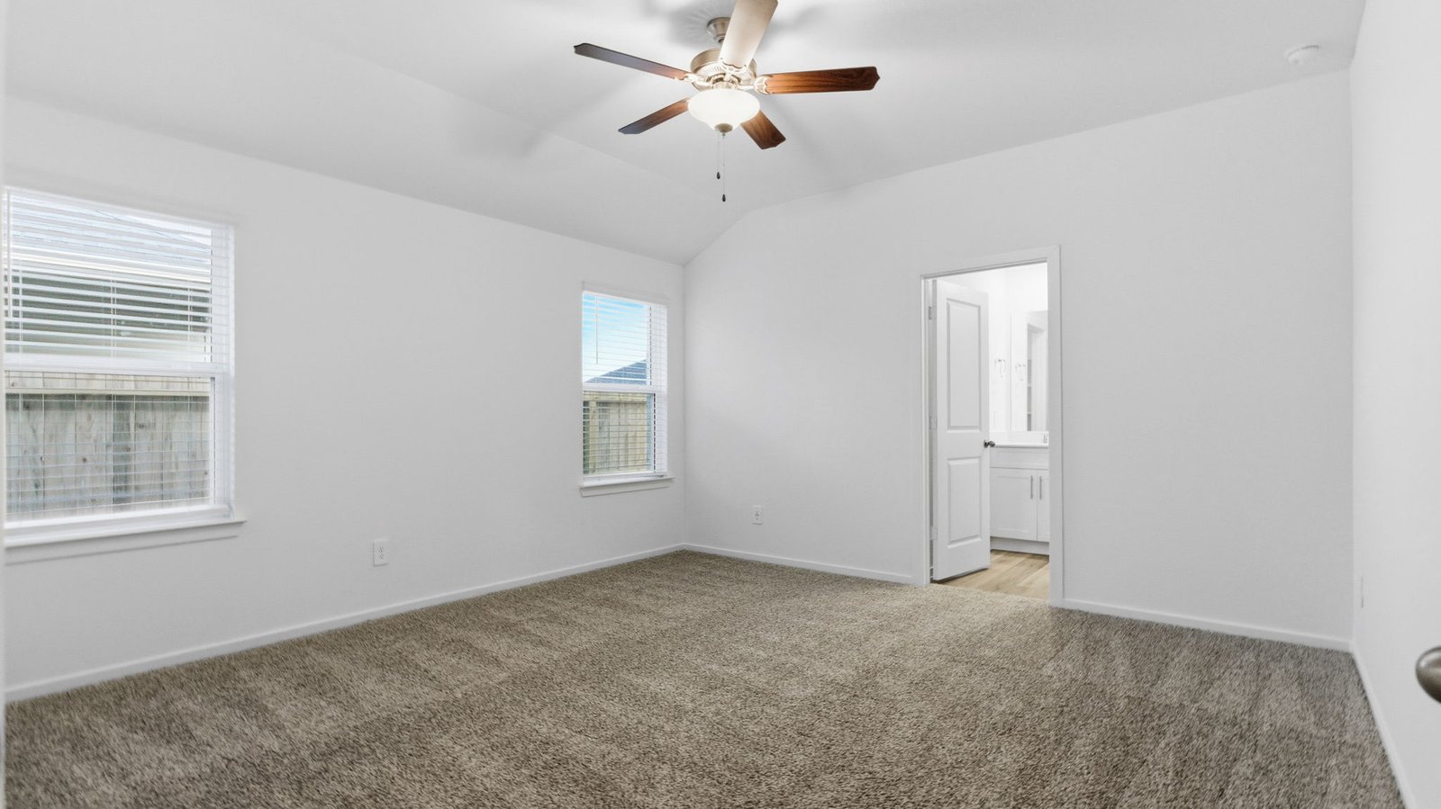 A spacious primary bedroom emphasizing open space and natural lighting with large windows.