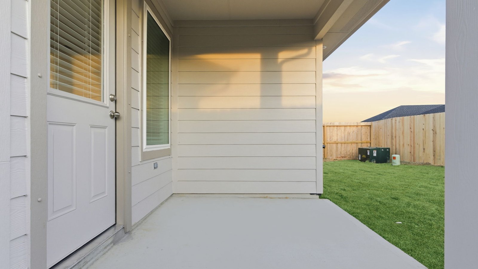Outdoor covered patio with seating area overlooking a well-maintained lawn, perfect for relaxation.