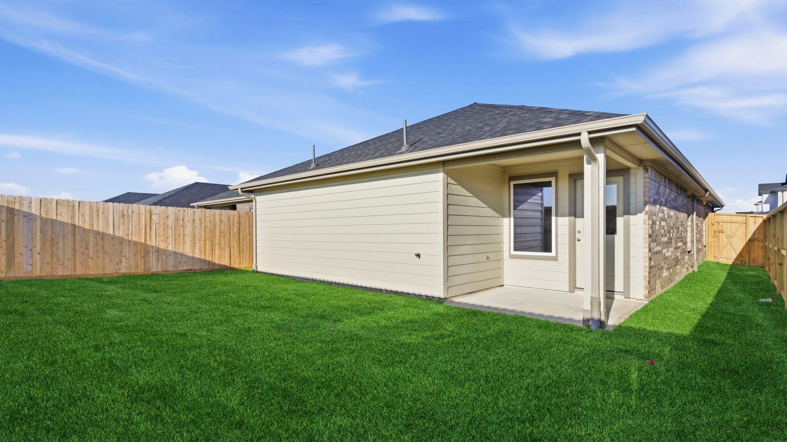 Outdoor covered patio with seating area overlooking a well-maintained lawn, perfect for relaxation.