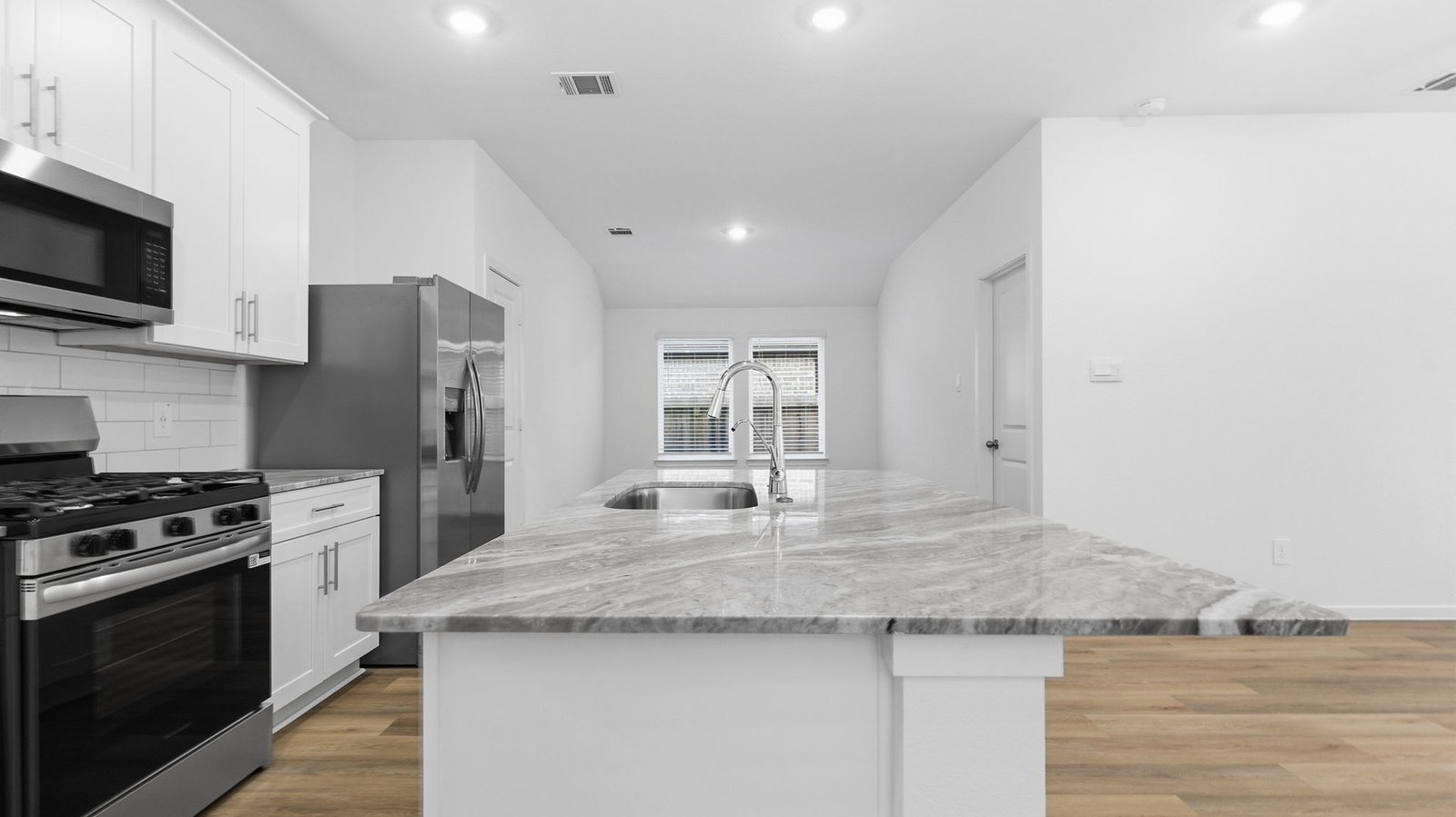 Bright and spacious kitchen with quartz countertops, stainless steel appliances, and an island with bar seating.