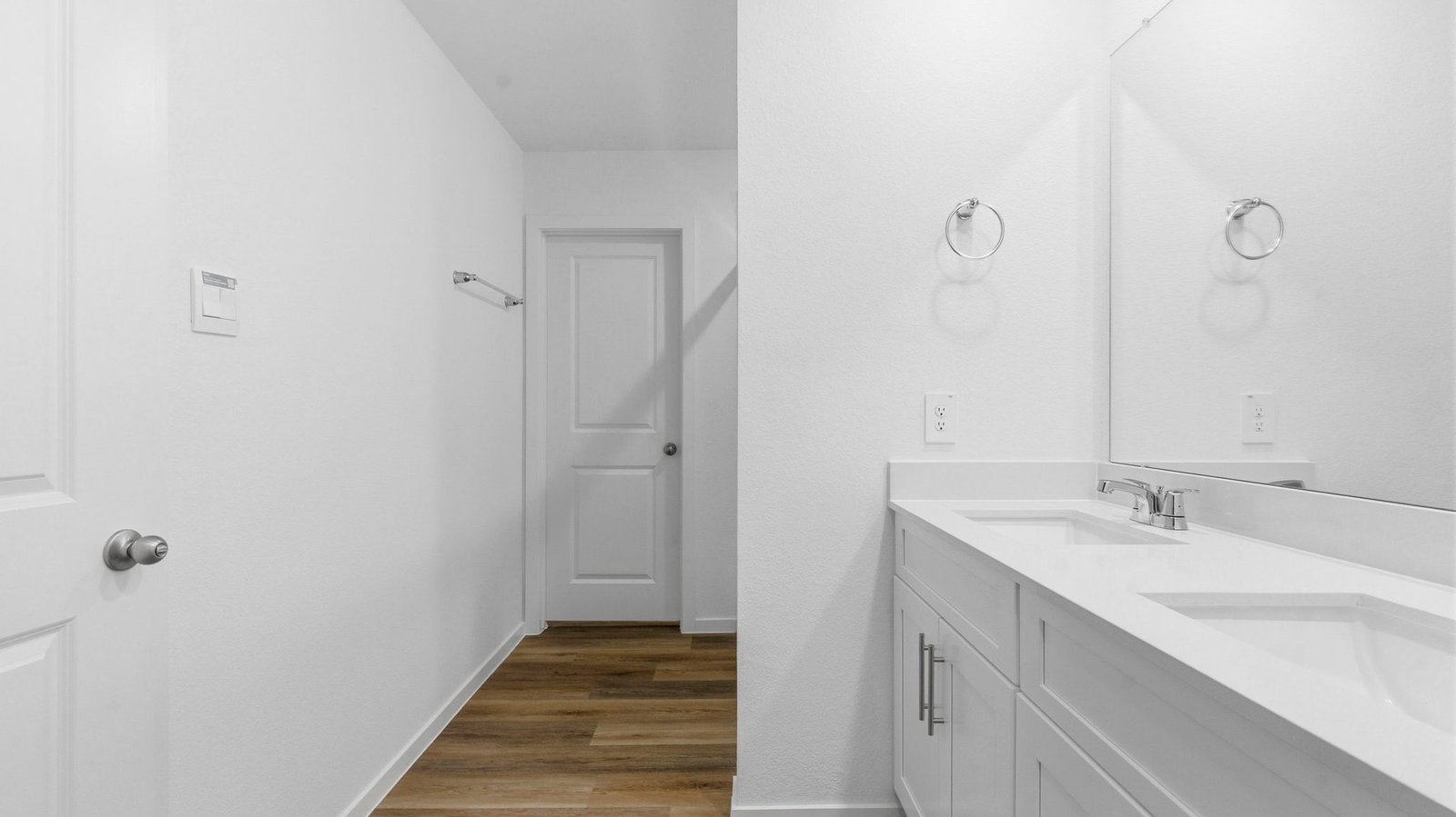 Modern primary bathroom with double vanities, granite countertops, and a glass-enclosed shower with a walk-in closet.