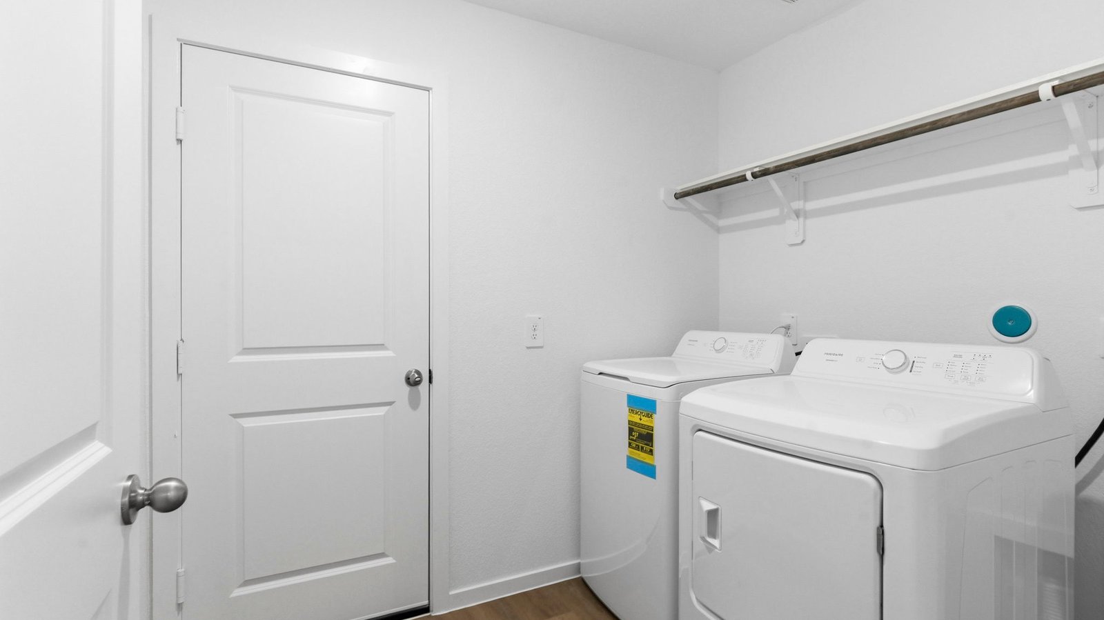 Spacious laundry room with washer and dryer connections, hanging rod, and vinyl wood flooring