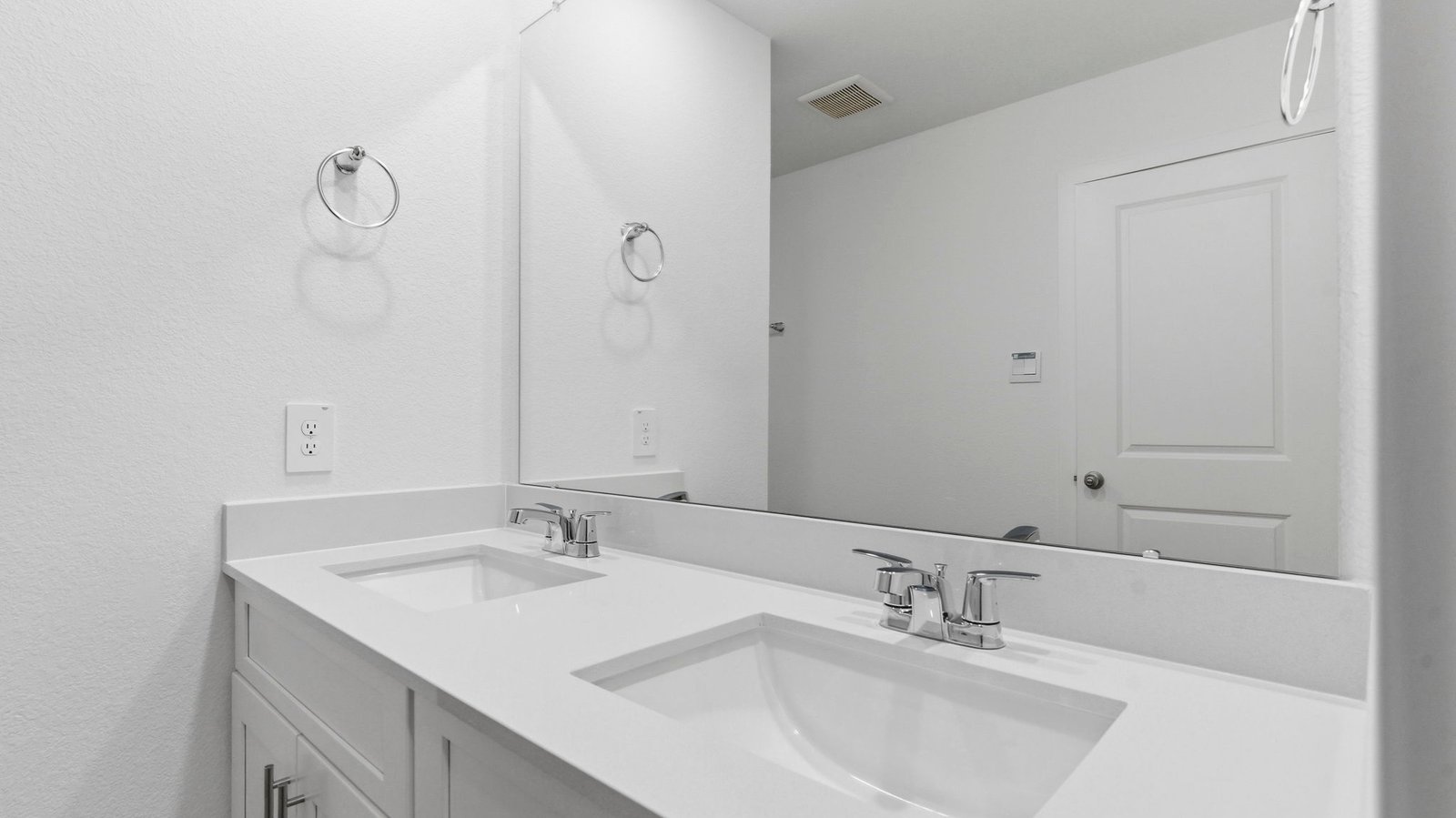 Modern primary bathroom with double vanities, quartz countertops, and a glass-enclosed shower with a walk-in closet.