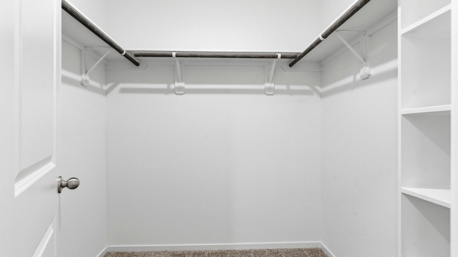 A spacious walk-in closet off the primary bathroom with multiple hanging rods, and shelves for maximum storage capabilities.