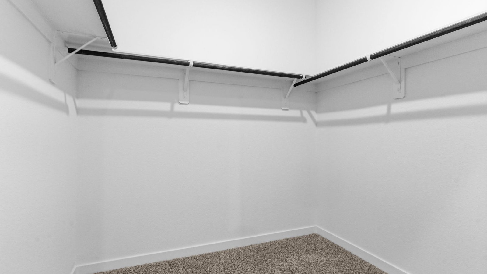 A spacious walk-in closet off the primary bathroom with multiple hanging rods, and shelves for maximum storage capabilities.