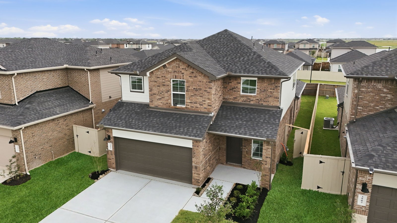 An aerial view of the newly built one story home with traditional architecture, a two car garage and a landscaped front yard