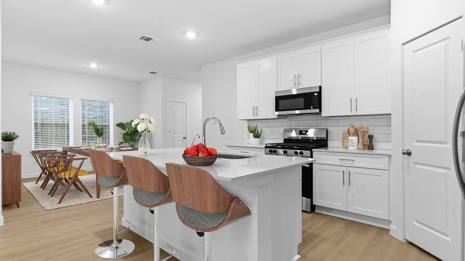 Bright and spacious kitchen with quartz countertops, stainless steel appliances, and an island with bar seating.