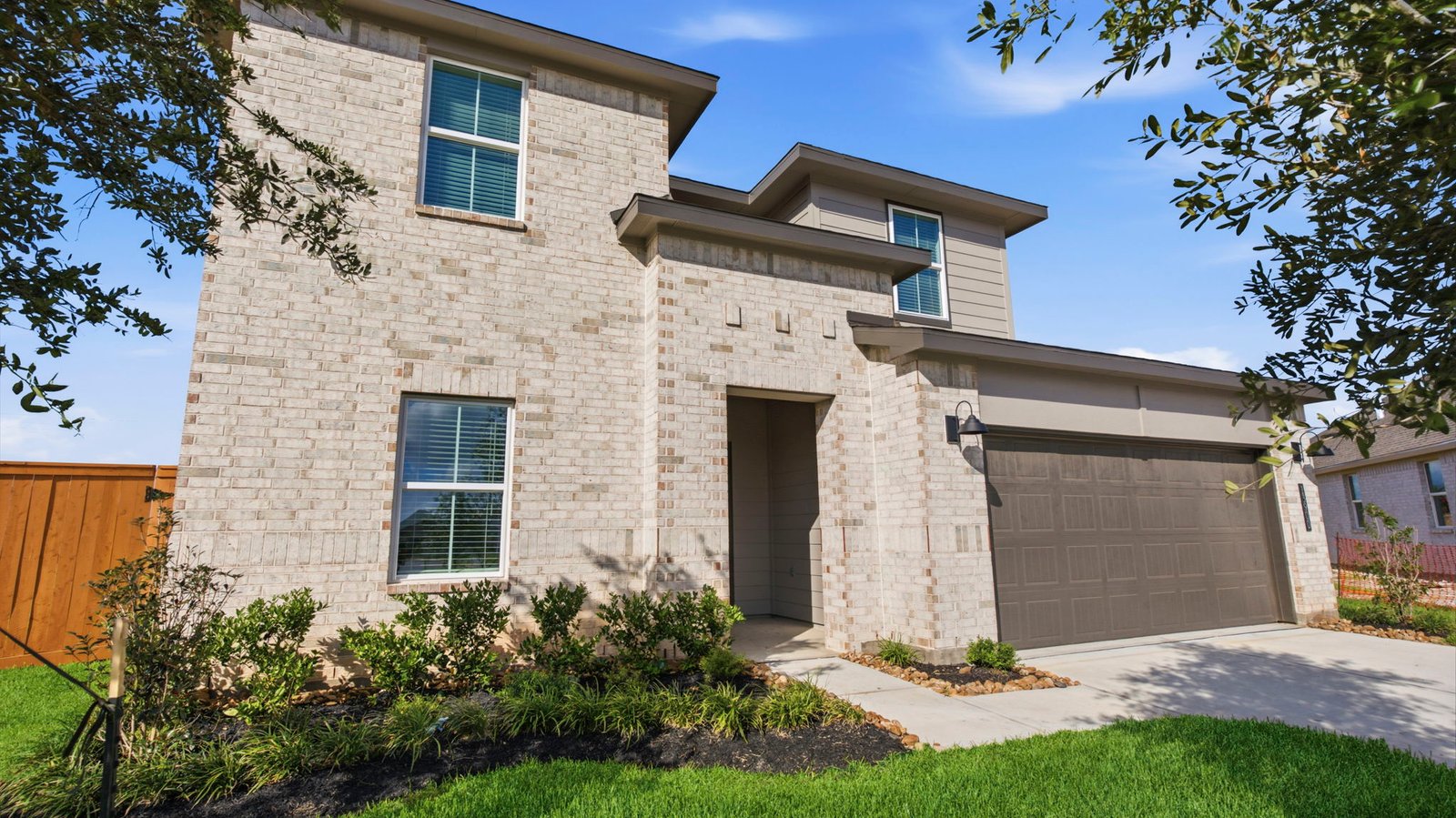 Newly built two story home with modern architecture, a double garage, and landscaped front yard.