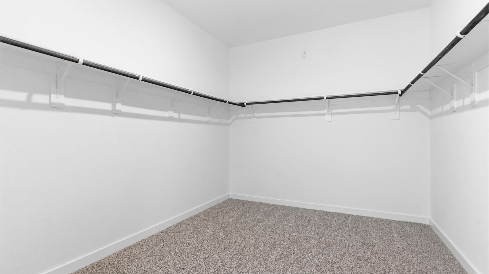 A spacious walk-in closet off the primary bathroom with multiple hanging rods, and shelves for maximum storage capabilities.