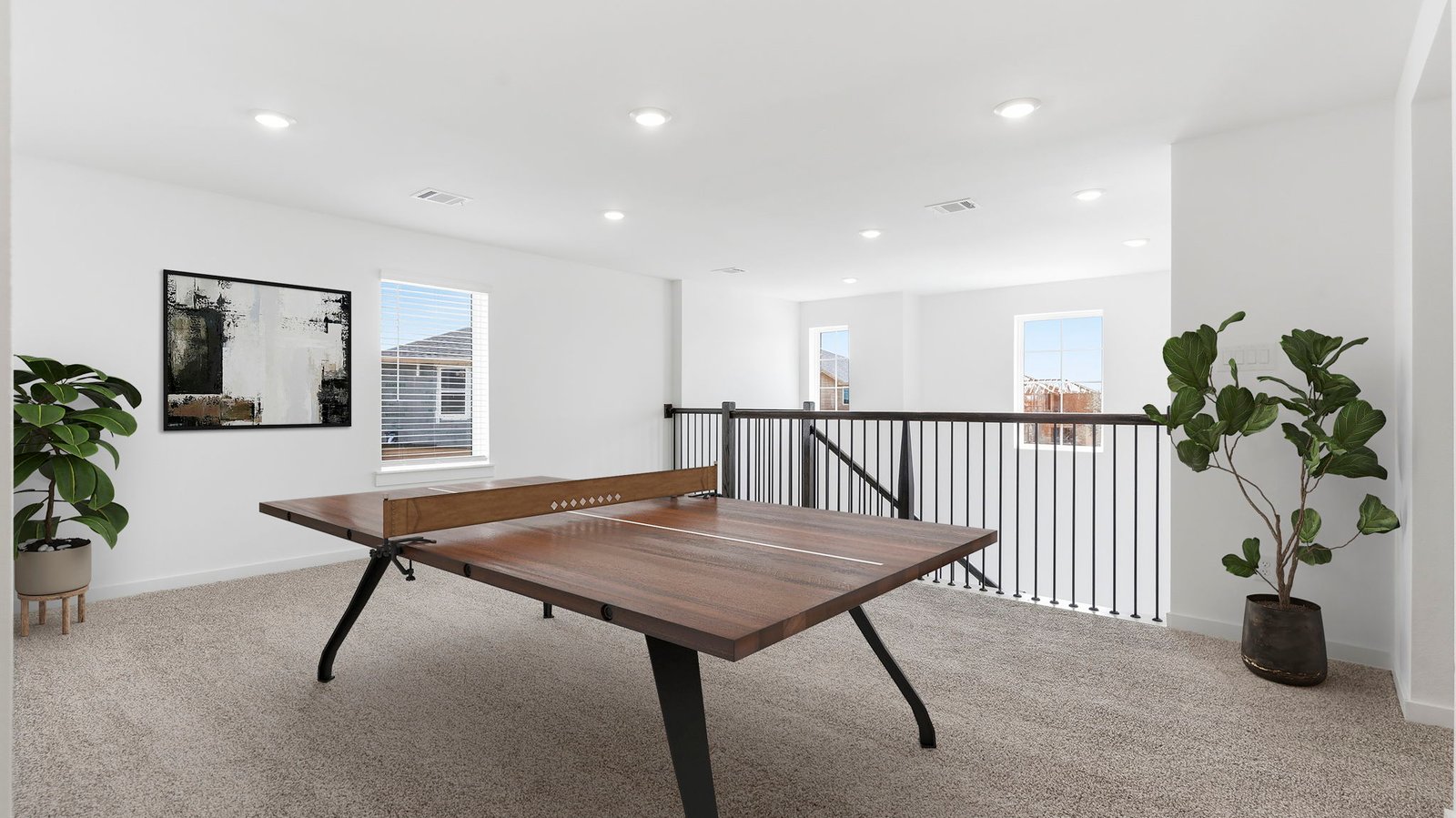 A spacious upstairs game room with plenty of natural light from windows overlooking side of the home