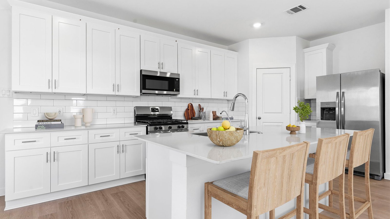 Bright and spacious kitchen with quartz countertops, stainless steel appliances, and an island with bar seating.