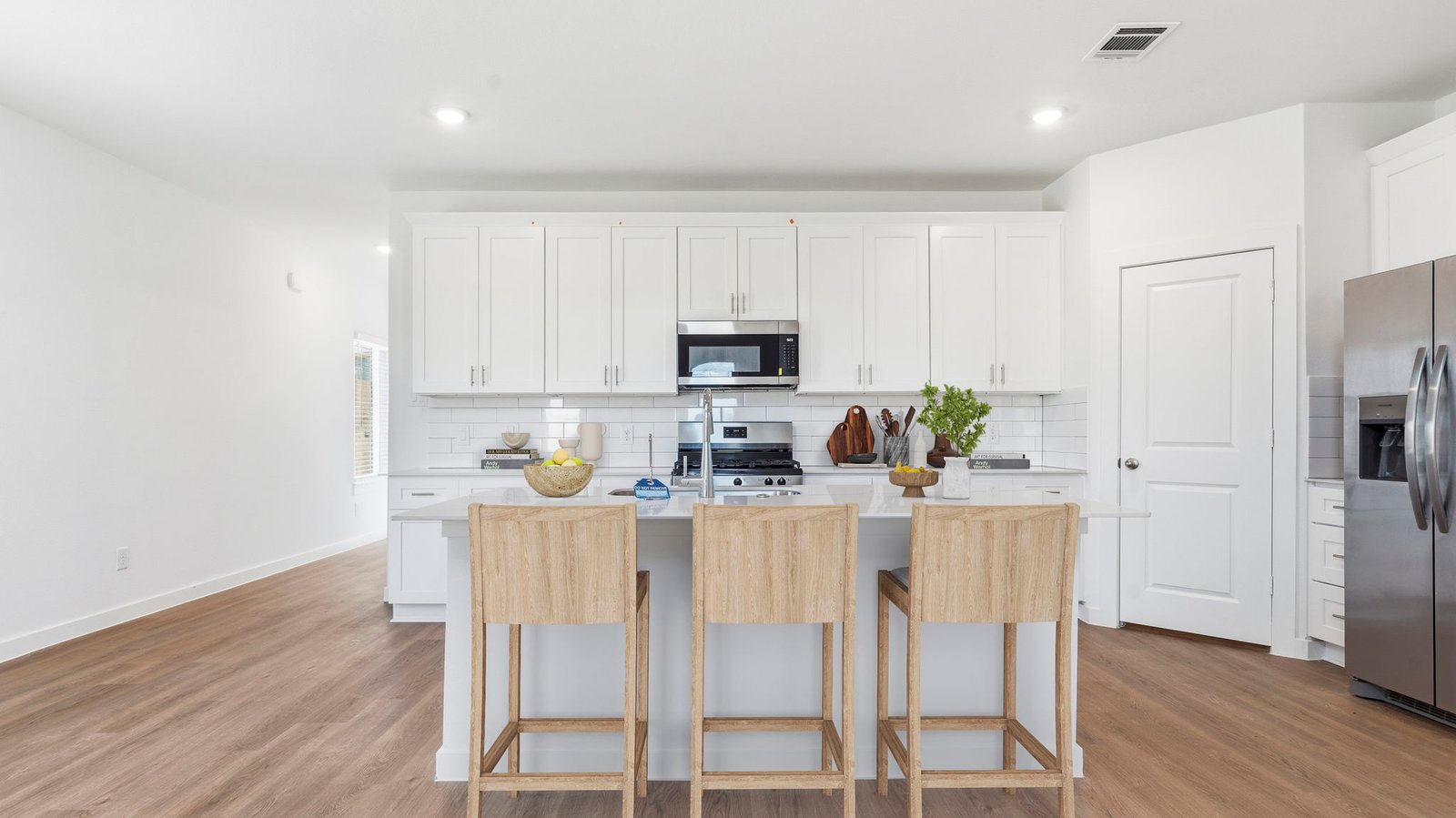 Bright and spacious kitchen with quartz countertops, stainless steel appliances, and an island with bar seating.