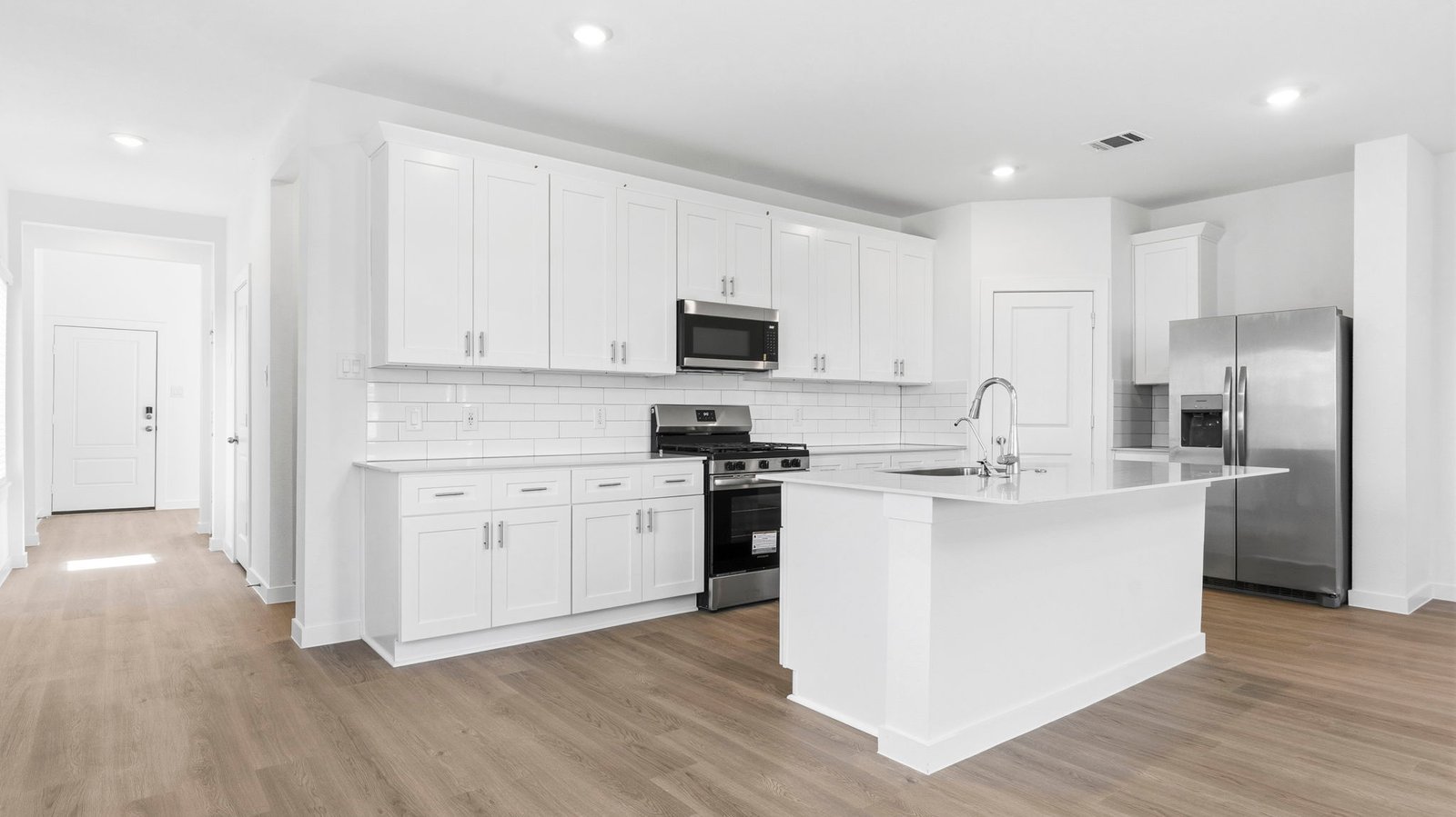 Bright and spacious kitchen with quartz countertops, stainless steel appliances, and an island with bar seating.